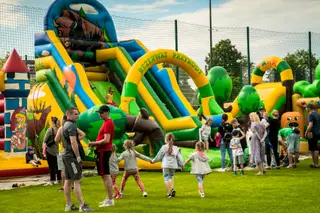 Zjeżdżalnia i dmuchane atrakcje z dalszego widoku na pikniku firmowym